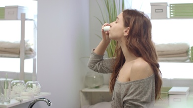 Woman using an antibacterial mouth rinse to help relieve canker sore pain.